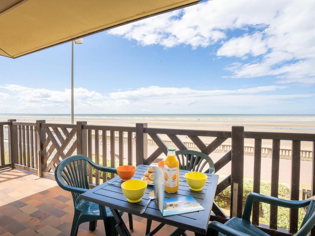 a table with drinks and chairs on a balcony with the beach at Apartment Cabourg Beach by Interhome in Cabourg