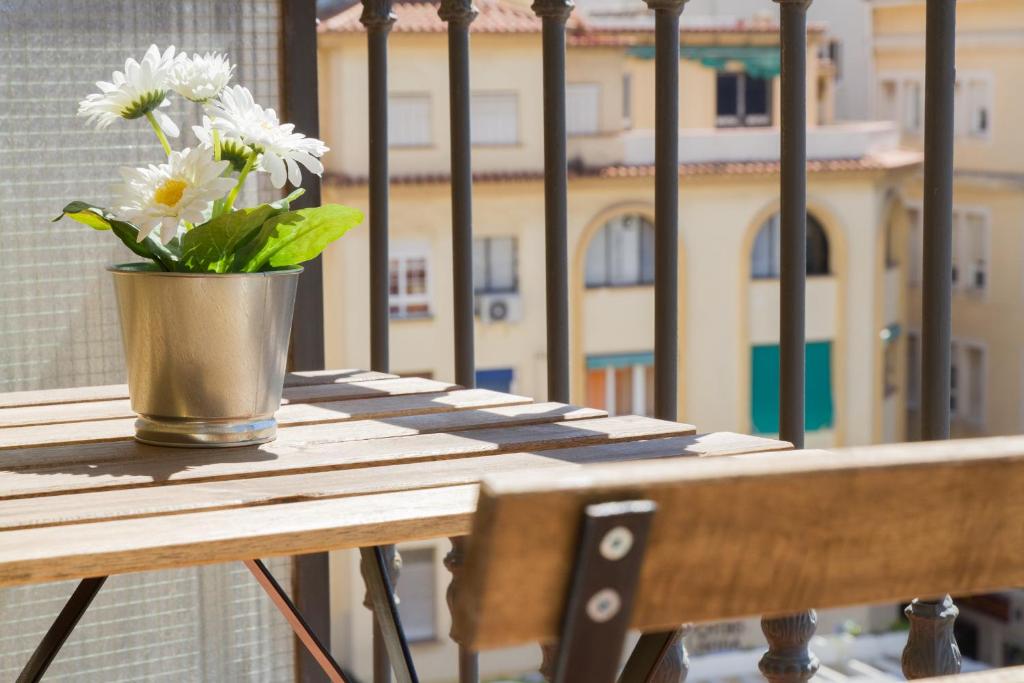 un vase de fleurs assis sur une table sur un balcon dans l'établissement Apartamentos Morgan, à Malaga