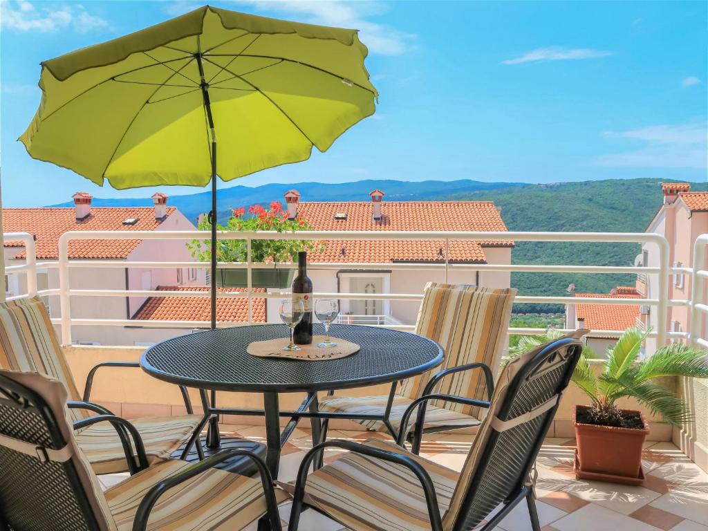 a table with a green umbrella on a balcony at Apartment Egle by Interhome in Rabac