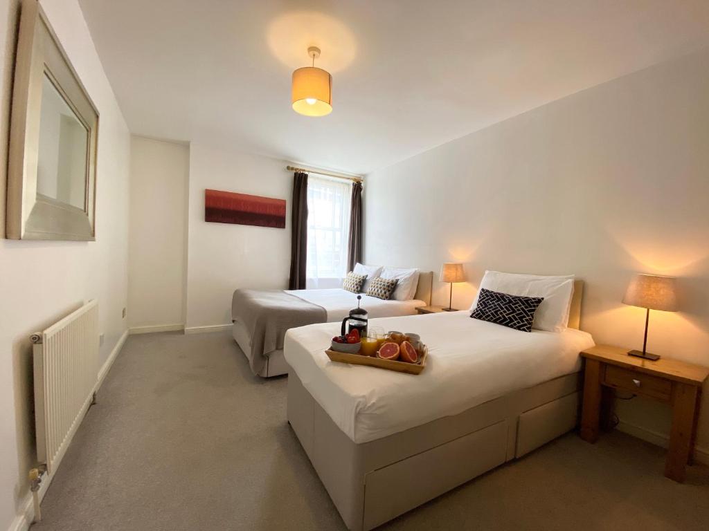 a bedroom with two beds with a tray of fruit on it at Apartment next to Victoria Station in London