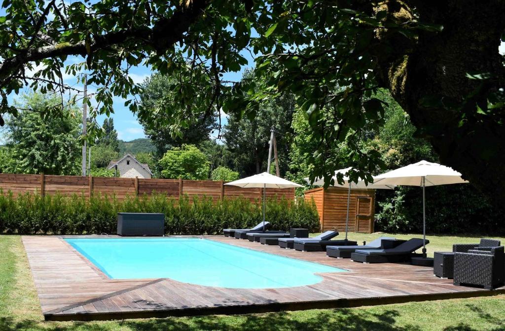 a swimming pool with chairs and umbrellas in a yard at La Marcillande in Saint-Cyprien