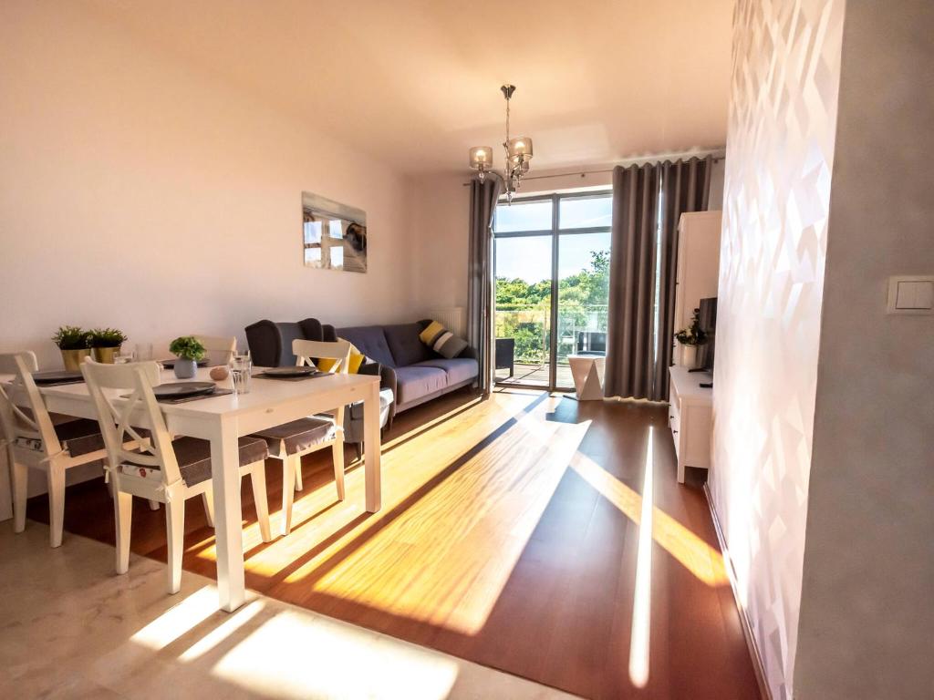 a dining room and living room with a table and chairs at VacationClub – Diune Apartament 60 in Kołobrzeg