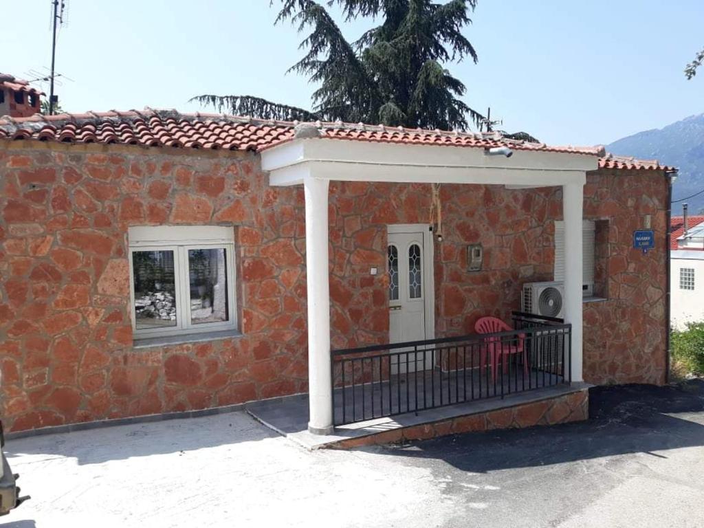 a small brick house with a porch and a door at Dimitris house in Kalabaka
