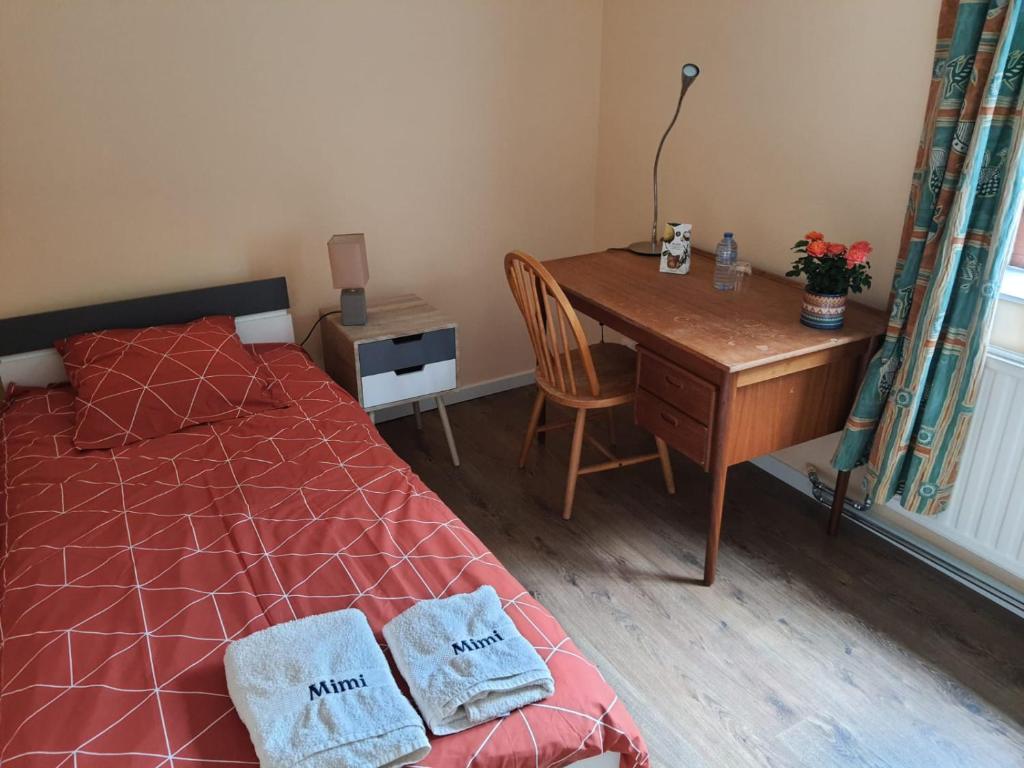 um quarto com uma secretária e uma cama com 2 toalhas em Chez Mimi - chambre vue jardin em Bruxelas