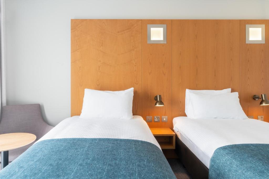 a hotel room with two beds and a table at Holiday Inn Bournemouth by IHG in Bournemouth