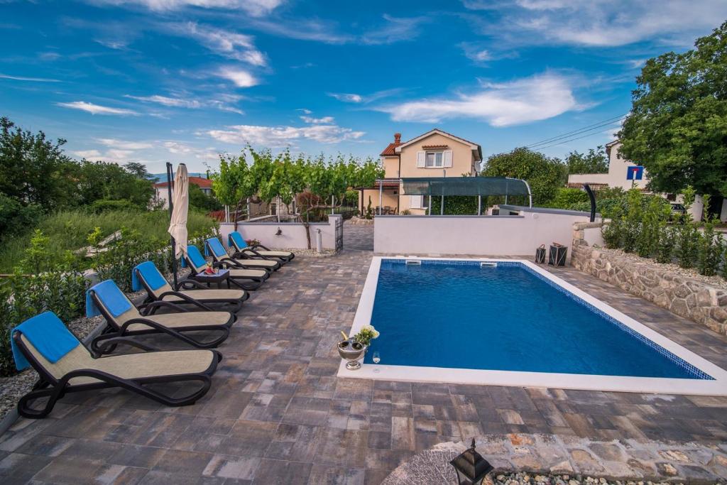 a pool with lounge chairs next to a house at Villa Marina in Malinska