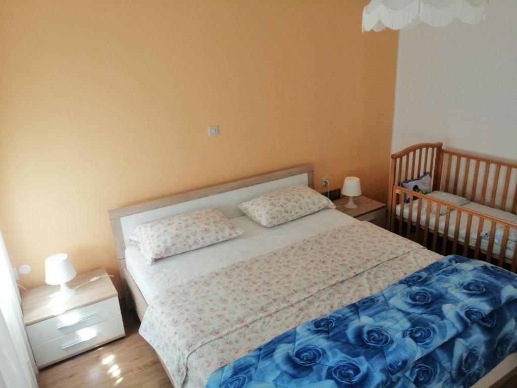 ein Schlafzimmer mit einem Bett mit blauer Bettwäsche und einem Kinderbett in der Unterkunft Apartma 2000 Tolmin in Tolmin