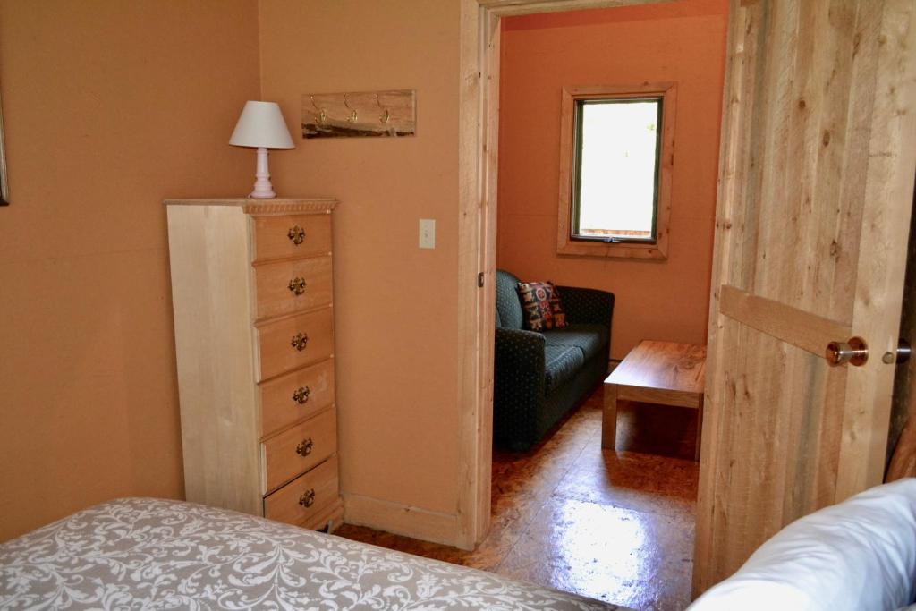 a bedroom with a door open to a living room at Schott's Lake Conference & Resort in Sundre