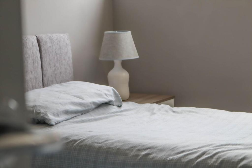 - une chambre avec un lit et une lampe sur une table dans l'établissement Trinidad House, à East Kilbride