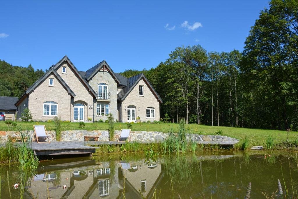 a large house with a pond in front of it at Czarny Dział in Wysowa-Zdrój