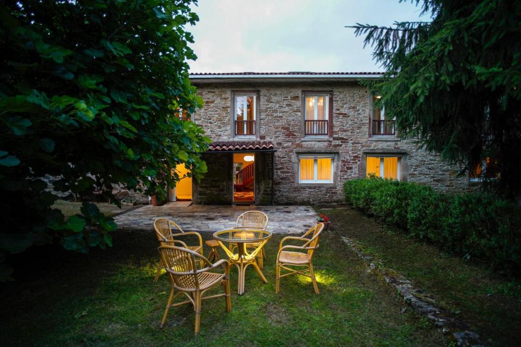 a table and chairs in front of a stone house at O Casal das Árbores in Santiago de Compostela