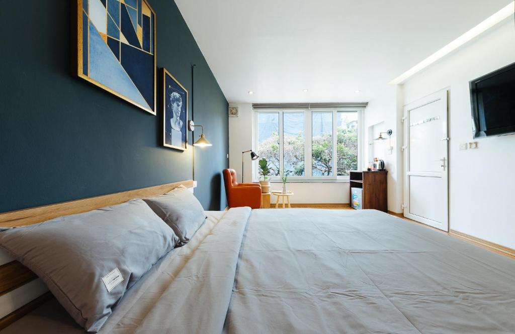 1 dormitorio con 1 cama grande y pared azul en Aimee House - Phan Bội Châu en Hanói