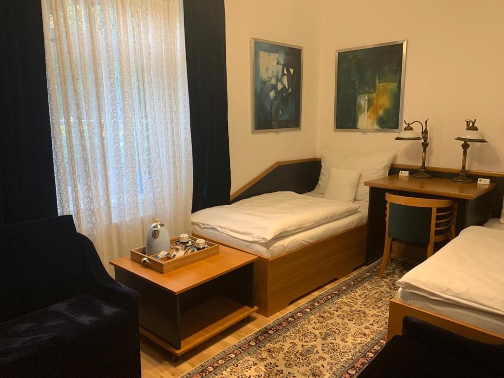 a room with two beds and a table and a desk at Antik Hotel Sofia in Litomyšl