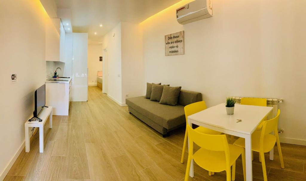 sala de estar con sofá, mesa y sillas amarillas en Moncloa-Arguelles nuevos pisos en Madrid