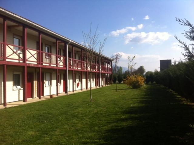 a large building with a grass field next to it at Couett' Hotel Rumilly in Rumilly