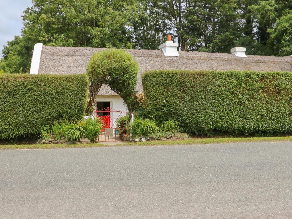una casa con techo de paja y puerta roja en Mary Rose Cottage en Castleisland