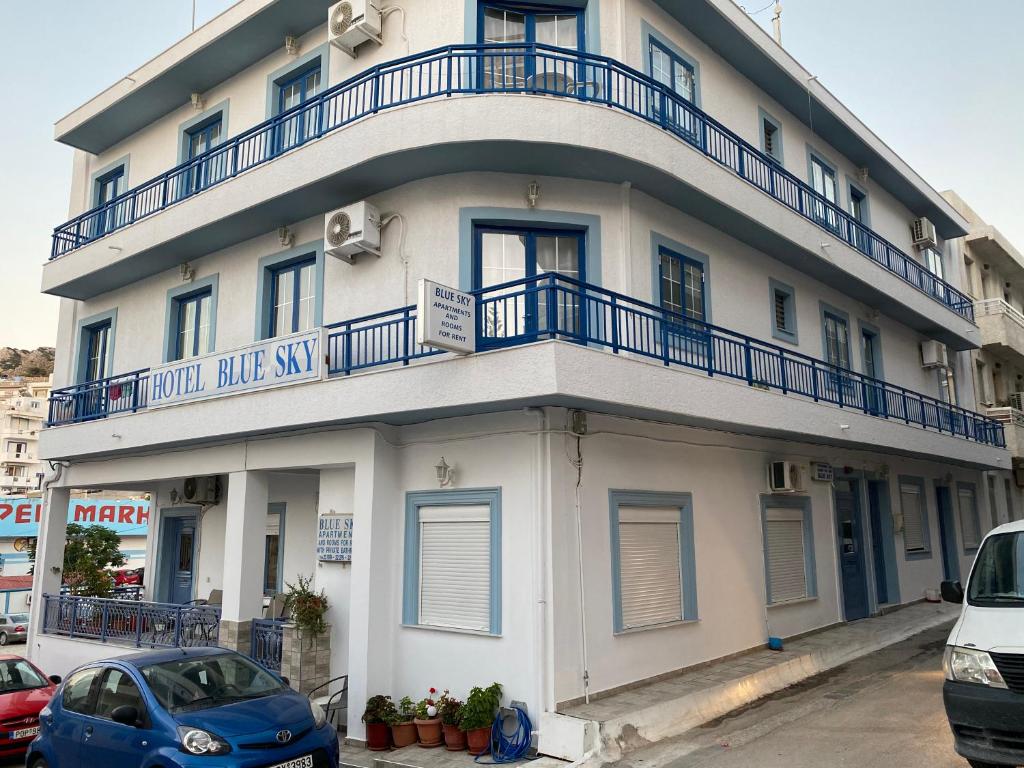 a white building with blue balconies on top of it at Blue Sky Apartments in Karpathos
