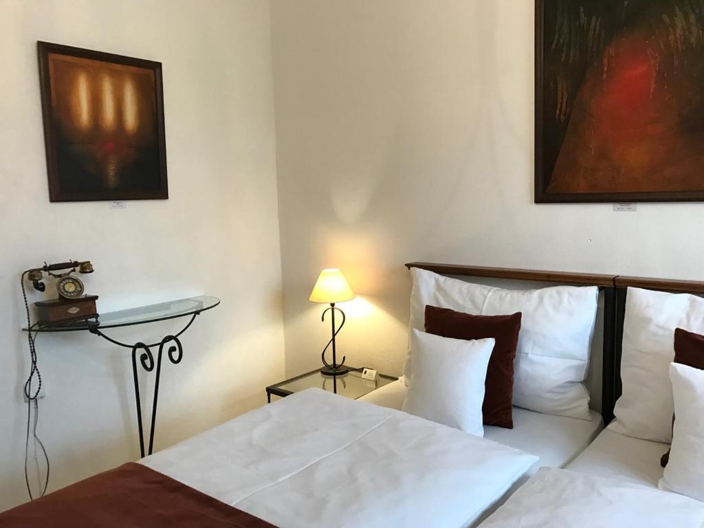 a bedroom with two beds and a table with a lamp at Antik Hotel Sofia in Litomyšl
