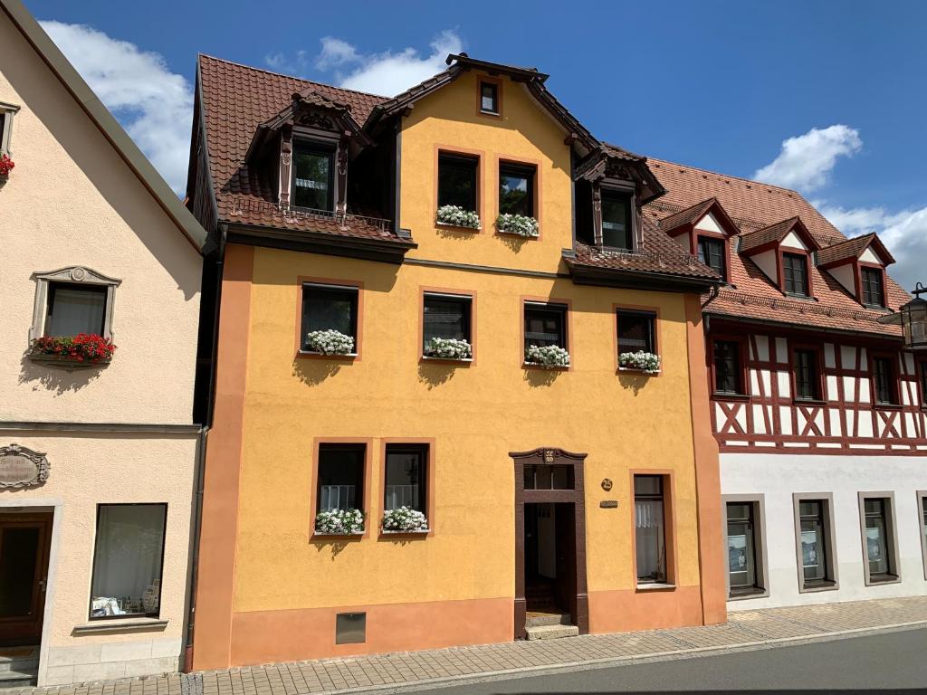 un bâtiment jaune avec des boîtes de fleurs sur les fenêtres dans l'établissement Villa Ammonit, à Pottenstein