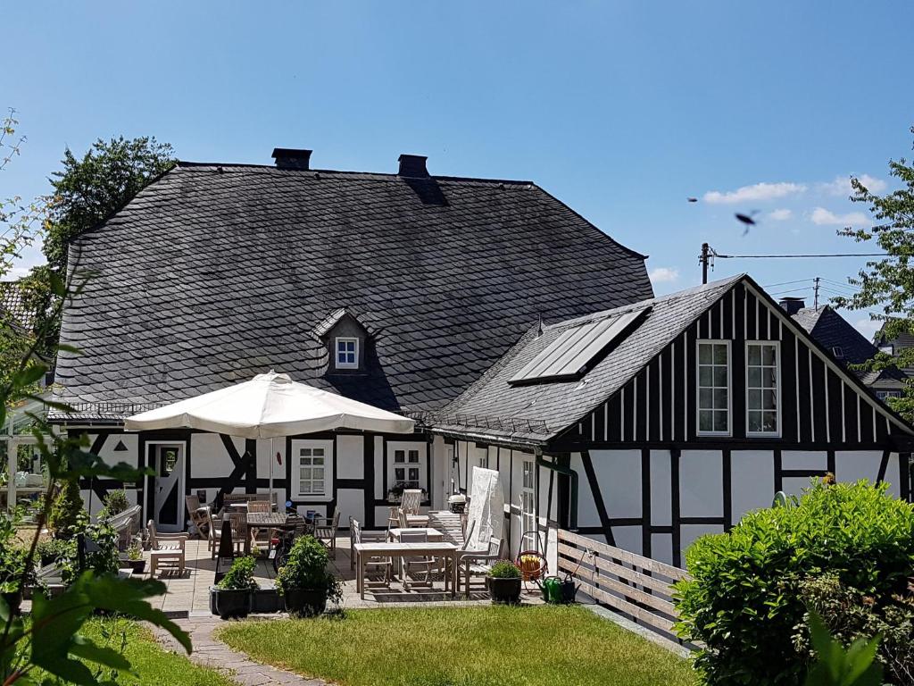 a black and white house with tables and umbrellas at Ferienwohnung Stickereimuseum Oberhundem in Kirchhundem