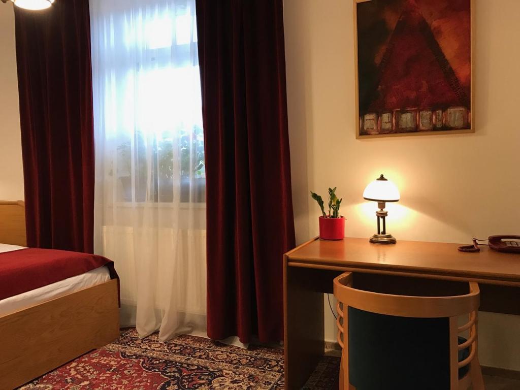 a bedroom with a bed and a desk and a window at Antik Hotel Sofia in Litomyšl