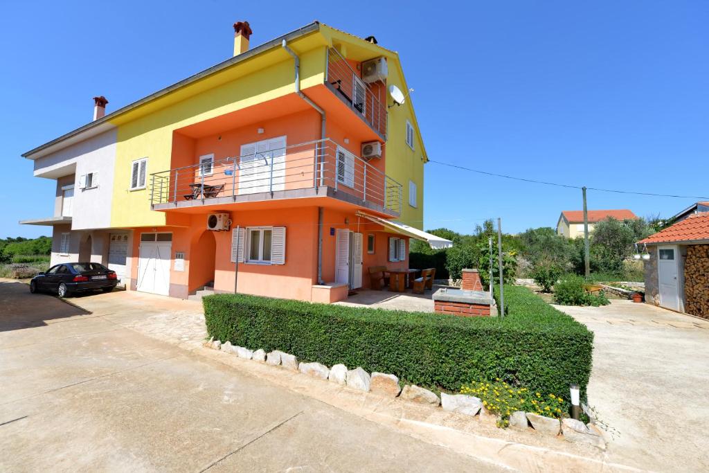 ein gelbes und orangefarbenes Haus mit Auffahrt in der Unterkunft Apartments Blaza in Božava