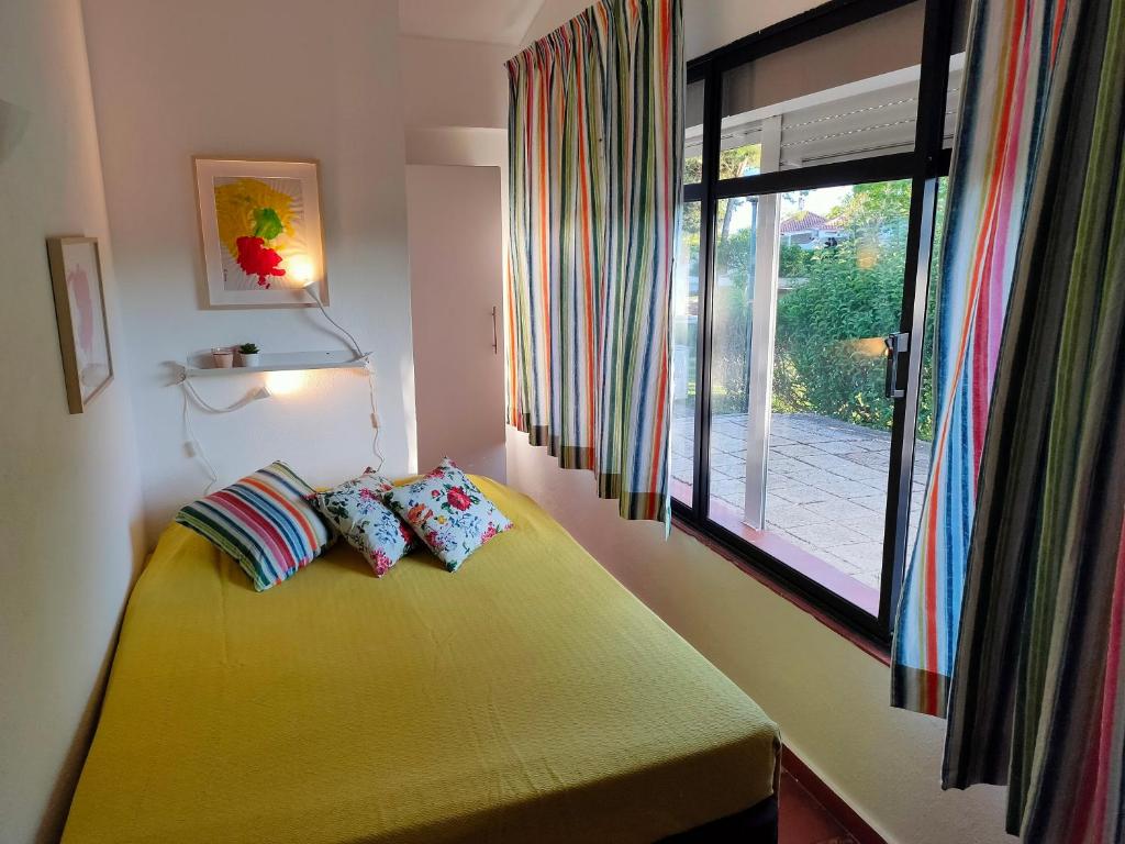 a bedroom with a yellow bed with a window at Studio Pedras d'el Rei in Santa Luzia