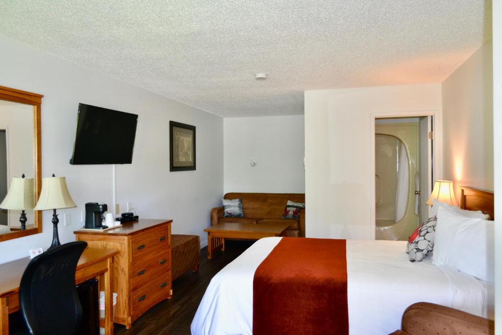 a hotel room with a bed and a desk and chair at Schott's Lake Conference & Resort in Sundre