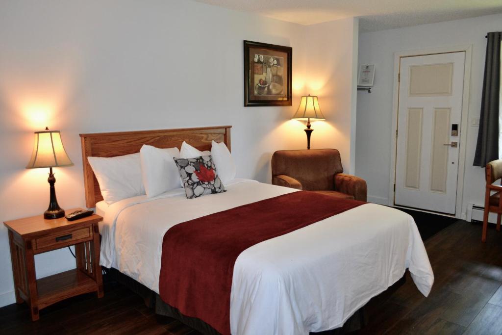 a hotel room with a large bed and a chair at Schott's Lake Conference & Resort in Sundre
