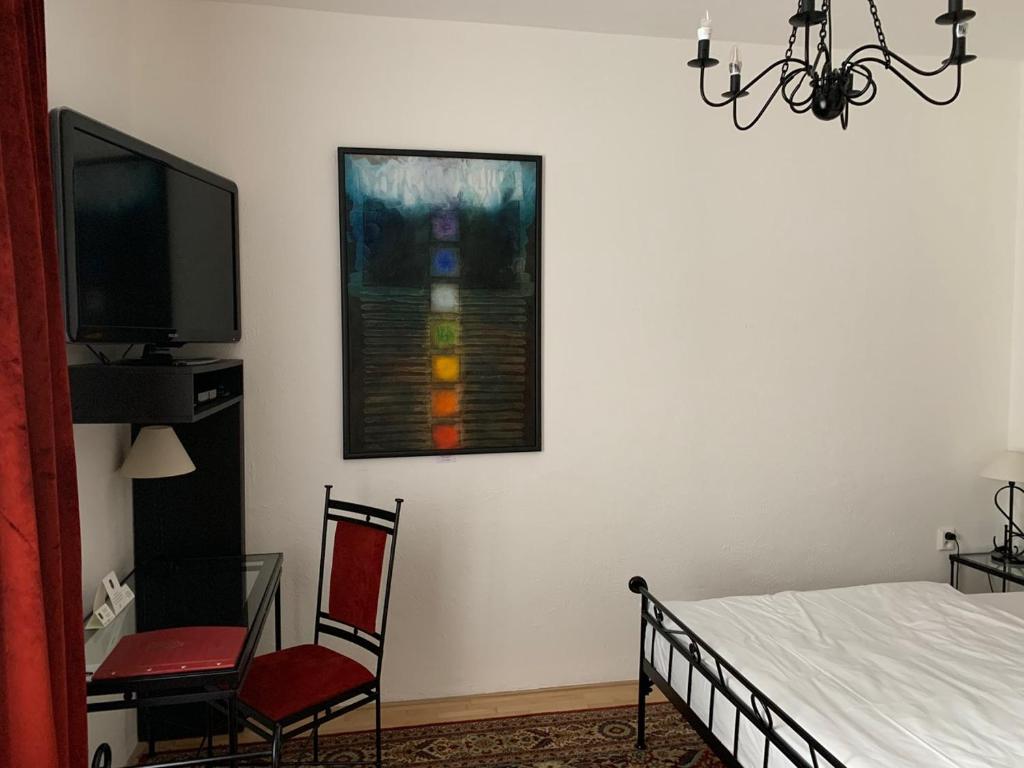 a bedroom with a bed and a tv and a chair at Antik Hotel Sofia in Litomyšl