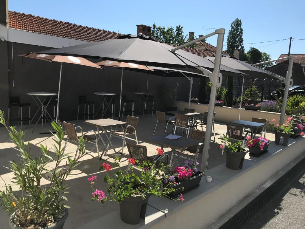 a patio with tables and chairs and an umbrella at Le toro bleu in Montier-en-Der