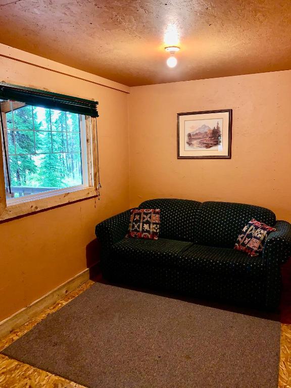 a living room with a black couch and a window at Schott's Lake Conference & Resort in Sundre