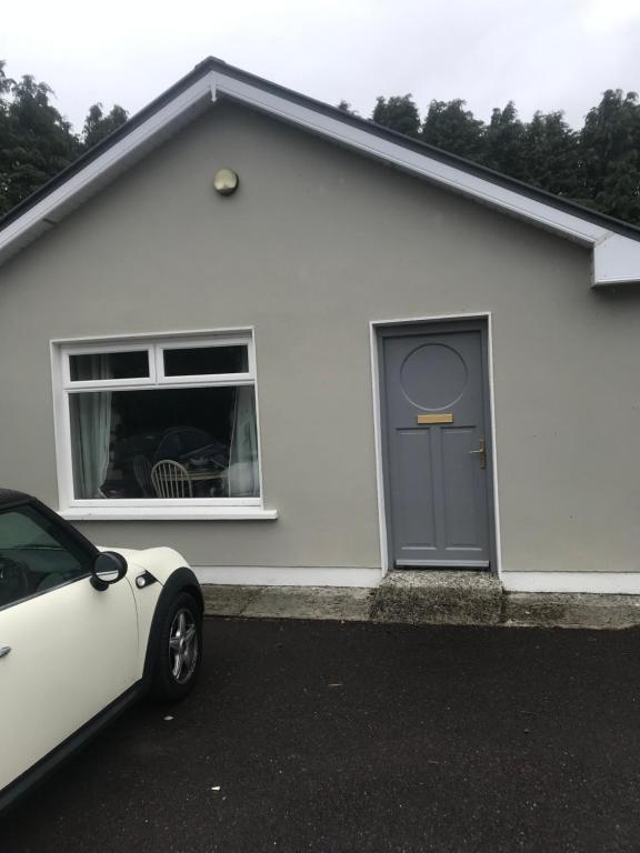 una casa blanca con un coche aparcado delante de ella en Kerry Air, en Killarney
