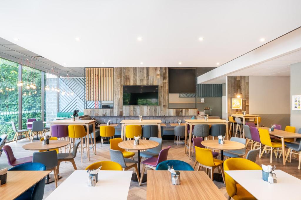 a restaurant with tables and chairs and windows at Holiday Inn Bournemouth by IHG in Bournemouth