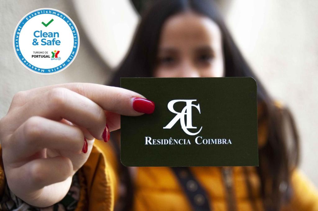 a woman holding a green card with a controller at Residencia Coimbra in Coimbra