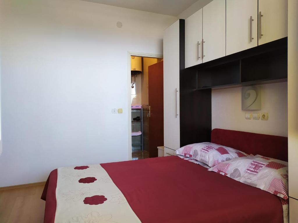 a bedroom with a bed with a red and white blanket at Apartman Nina in Makarska