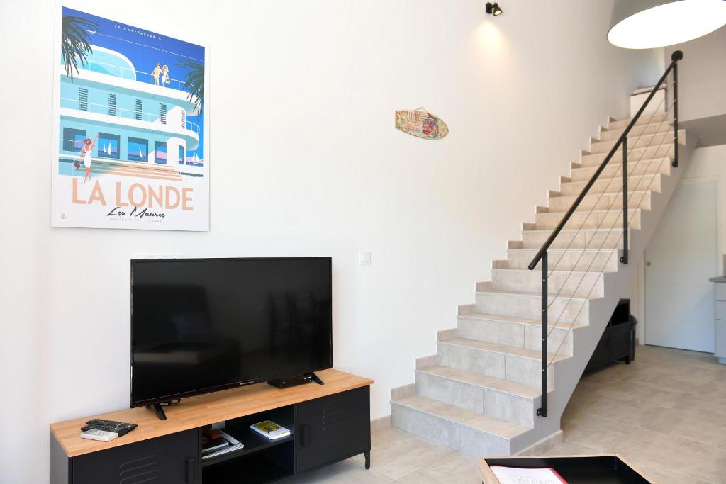 a living room with a tv and a staircase at Sous Les Pins gîtes et chambres d'hôtes in La Londe-les-Maures