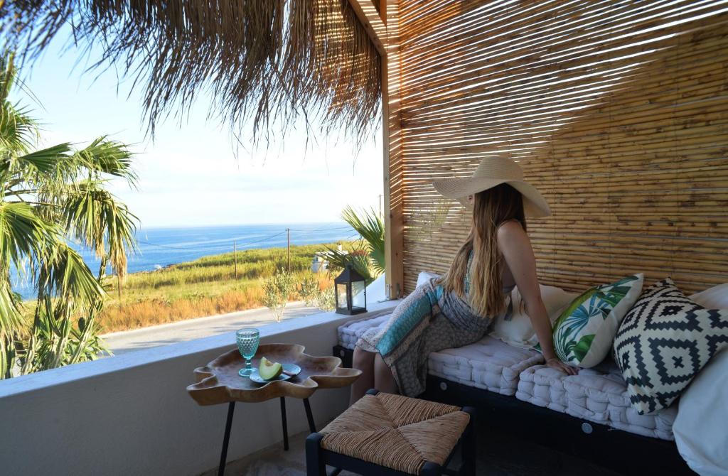 una mujer sentada en un sofá mirando hacia el océano en Aloe Mare Suites en Liaropá