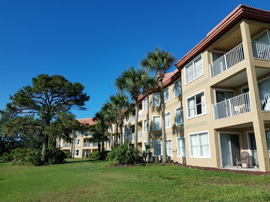 a large apartment building with palm trees in the foreground at Parc Corniche Condominium Suites in Orlando