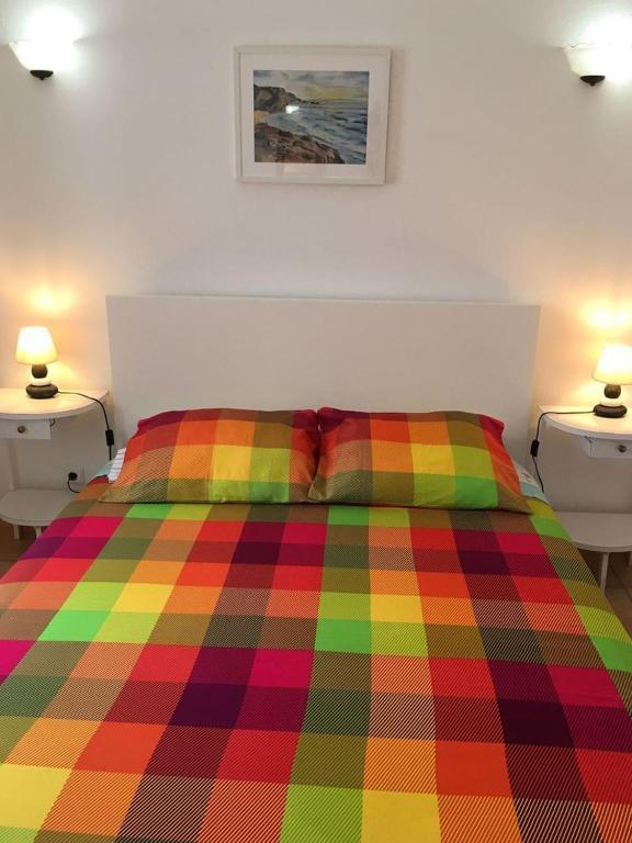 a colorful bed in a bedroom with two lamps at Carrapateira Lodge in Carrapateira