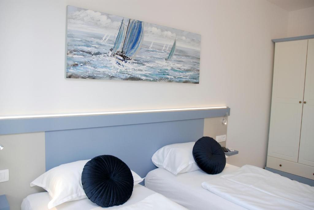 ロヴィニにあるB&B Sea Joy Rovinjの壁に絵画が飾られた部屋のベッド2台