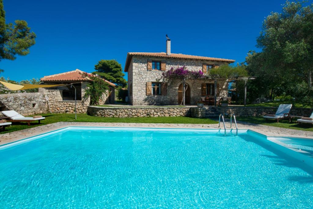a villa with a swimming pool in front of a house at Palagio di Orio Villas in Apolpaina