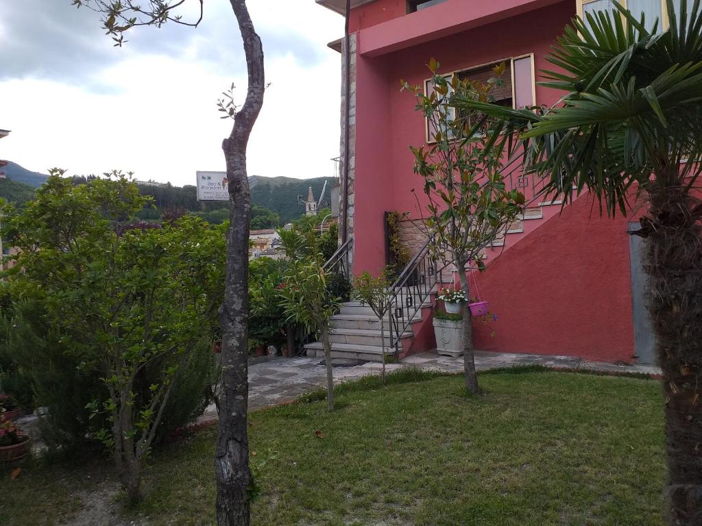 ein rosafarbenes Haus mit einem Fenster und einigen Bäumen in der Unterkunft Bed & Breakfast La Rosa Rossa in Cagli