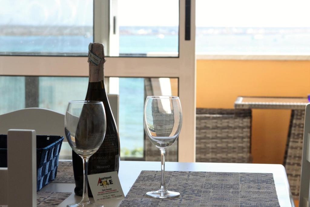 アルゲーロにあるAppartamenti Soleのワイン1本とワイングラス2杯(テーブル上)