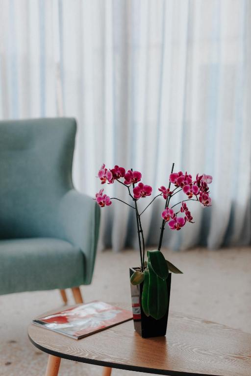 a vase with pink flowers on a table next to a chair at Vivari Acta in Vivari