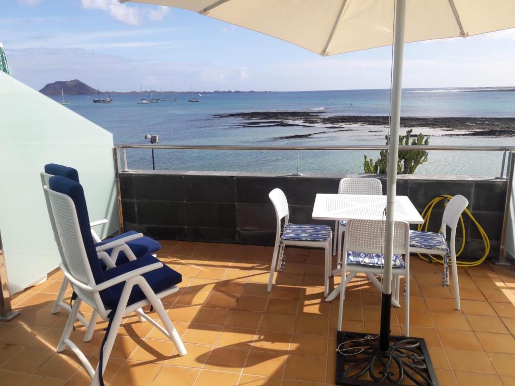 patio ze stołem, krzesłami i parasolem w obiekcie Mar de fuerteventura w Corralejo