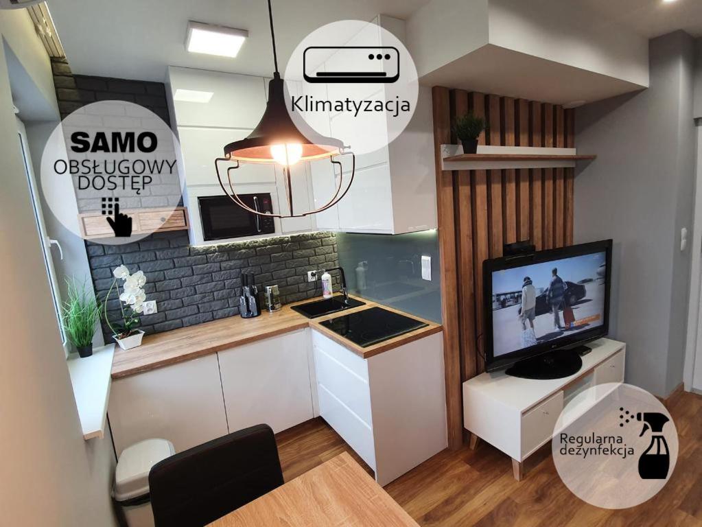 a small kitchen with a sink and a tv at Iława Apartamenty in Iława