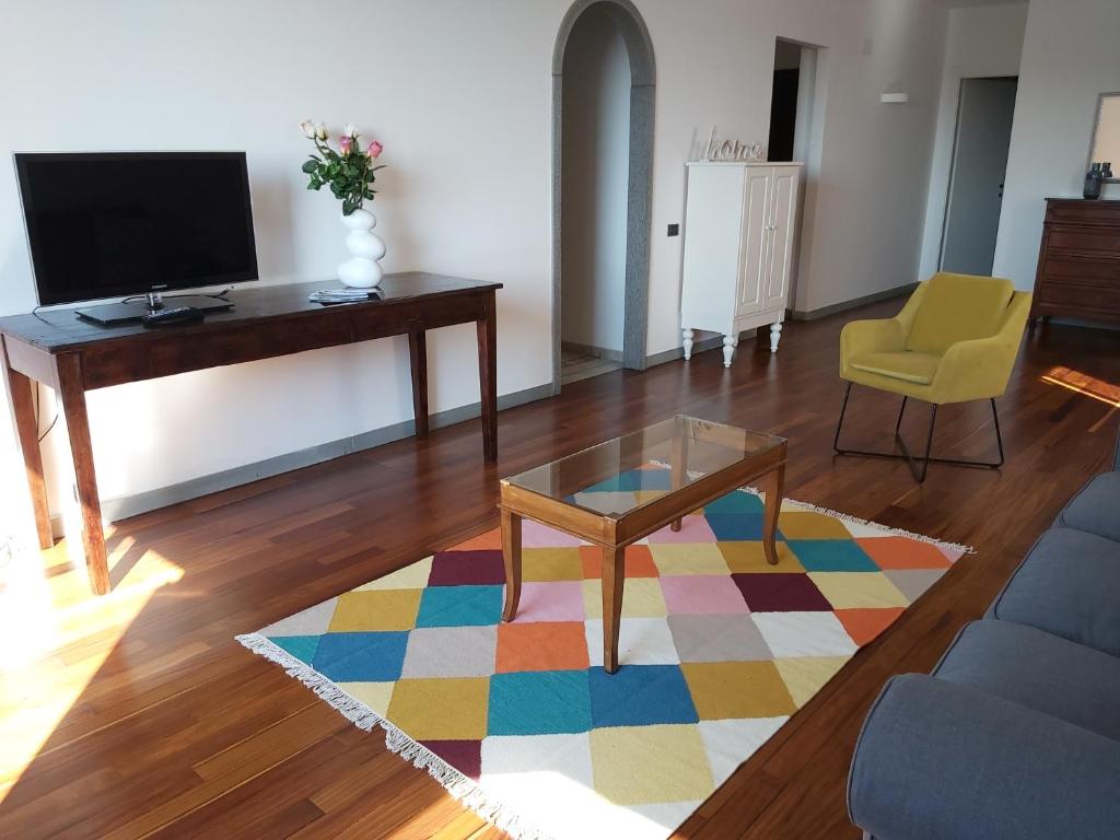 uma sala de estar com uma televisão, uma mesa e um tapete em Beach House em Piombino
