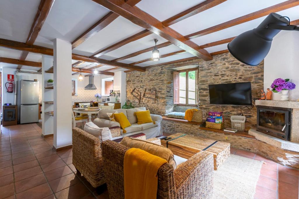 uma sala de estar com um sofá e uma lareira em Casas del Molino - Muiños do Mainzoso Turismo Rural em Paderne