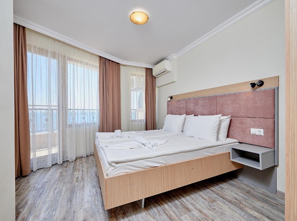 a bedroom with a large bed and a large window at Crotiria Beach - Aparthotel in Pomorie